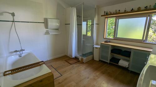 Un baño con bañera, lavabo y ducha. en Wooden house with indoor pool, en Saint-Médard-dʼAunis