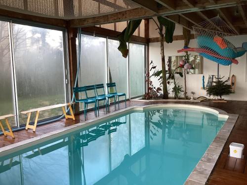 une grande piscine avec deux chaises bleues dans l'établissement Wooden house with indoor pool, à Saint-Médard-dʼAunis