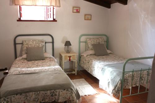 a bedroom with two beds and a table with a lamp at Casa Rural Tintilla in Vega de San Mateo