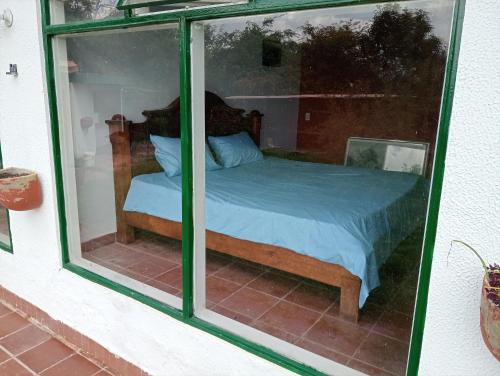 a bedroom with a bed through a glass window at La Juana Posada en Tenjo in Tenjo