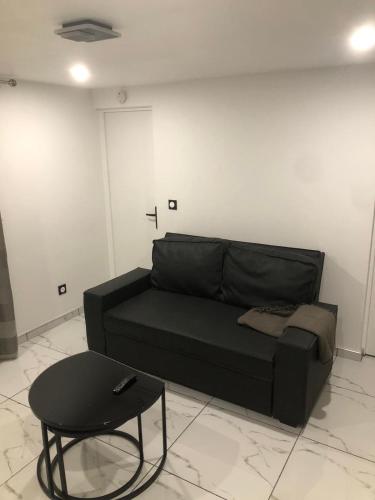 - un canapé noir et une table dans une chambre dans l'établissement Cozy and well located apartment, à Tremblay-en-France