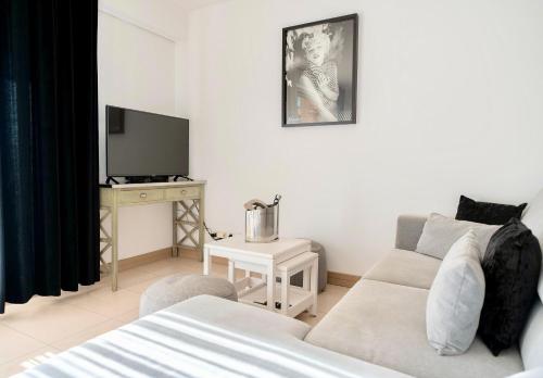 un salon avec un canapé et une télévision dans l'établissement Le Aix Rotonde Mirabeau - Centre Ville Terrasse Garage, à Aix-en-Provence