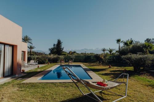 a swimming pool with a chair next to a house at Les Roses By La Siredrah in Marrakech