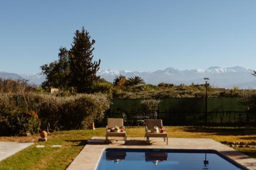 a backyard with two chairs and a swimming pool at Les Roses By La Siredrah in Marrakech