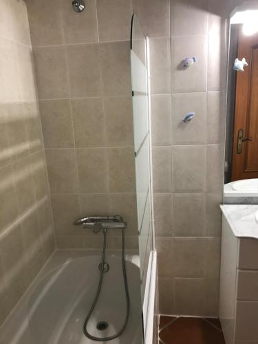 a bathroom with a shower with a tub and a sink at Ericeira Beach House in Ericeira
