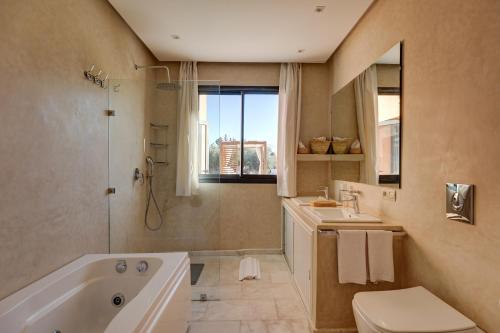 a bathroom with a tub and a toilet and a sink at Les Roses By La Siredrah in Marrakech