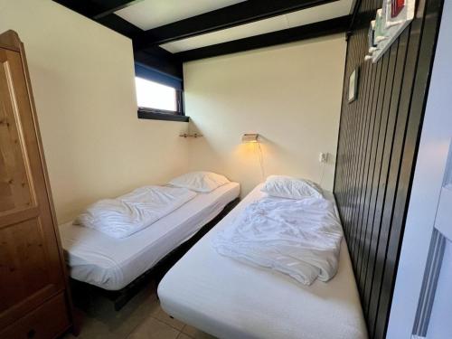 two beds in a small room with white sheets at Bungalow for 4 people in Wildrijk in Sint Maartenszee
