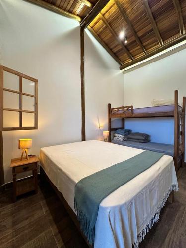 a bedroom with a large bed and a table with a lamp at Rancho Recanto da Serra in Delfinópolis