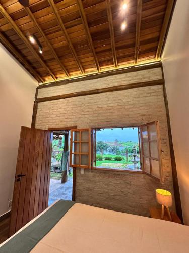 a bedroom with a bed and a window at Rancho Recanto da Serra in Delfinópolis