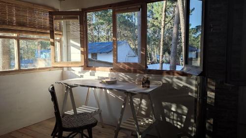 a table and chair in a room with windows at Hermosa Cabaña a 400mt del mar in Rocha