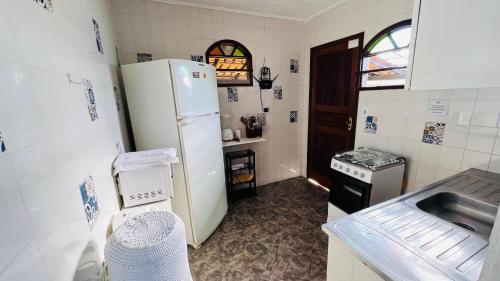 a small kitchen with a refrigerator and a sink at Casa Bem-te-vi - Passarim Hospedagem in Cumuruxatiba