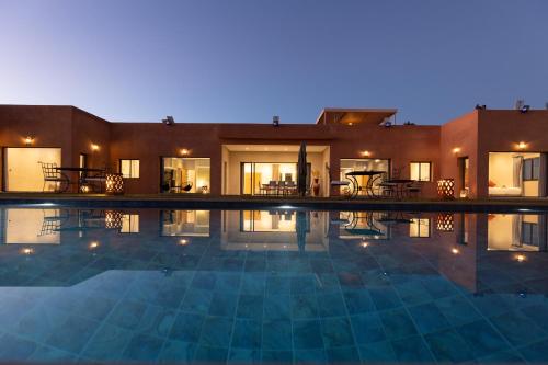 a house with a swimming pool at night at Les Roses By La Siredrah in Marrakech