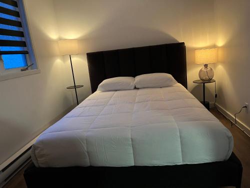 a bedroom with a large white bed with two lamps at Auberge Matha in Saint-Jean-de-Matha
