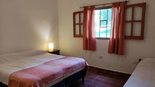 ein Schlafzimmer mit einem Bett und einem Fenster mit roten Vorhängen in der Unterkunft Don Juan M Cabañas in Villa Las Rosas