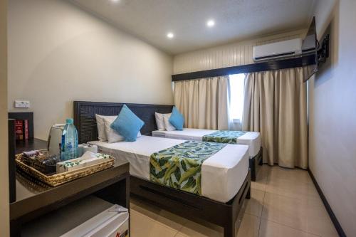 a hotel room with two beds and a window at Fiji Gateway Hotel in Nadi