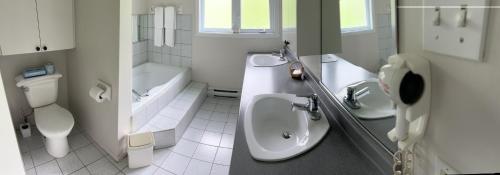 a bathroom with two sinks and a toilet and a tub at Auberge Matha in Saint-Jean-de-Matha
