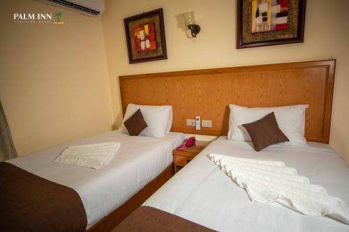 two beds sitting next to each other in a room at Palm Inn Hotel Hurghda in Hurghada