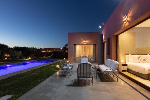 a bedroom with a bed and chairs next to a pool at Les Roses By La Siredrah in Marrakech