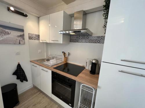 a small kitchen with a sink and a stove at Cosy Duplex ! Situation centrale - proche plage et commerces - linge de lit et serviettes de toilette compris in Ouistreham