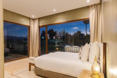 a bedroom with a white bed and a large window at Les Roses By La Siredrah in Marrakech