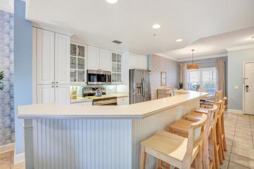 a kitchen with white cabinets and a bar with chairs at Near Beach & Coligny Plaza, Pool, Hot Tub, Patio in Hilton Head Island