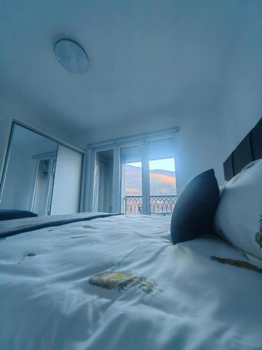 a bedroom with a large white bed with windows at Apartman Nermin in Travnik