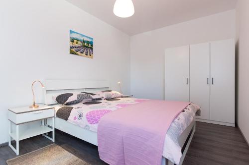 a white bedroom with a bed and a white cabinet at Apartments Stella in Krk
