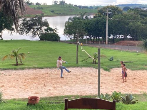 a man and two children playing a game in the sand at Rancho Recanto da Serra in Delfinópolis