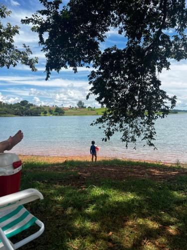 a young boy standing by the water holding a frisbee at Rancho Recanto da Serra in Delfinópolis