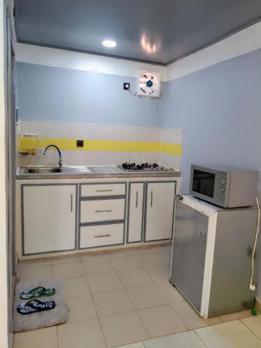 a kitchen with a refrigerator and a microwave at Ndouha House in Bafoussam