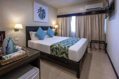 a bedroom with a large bed with blue pillows at Fiji Gateway Hotel in Nadi