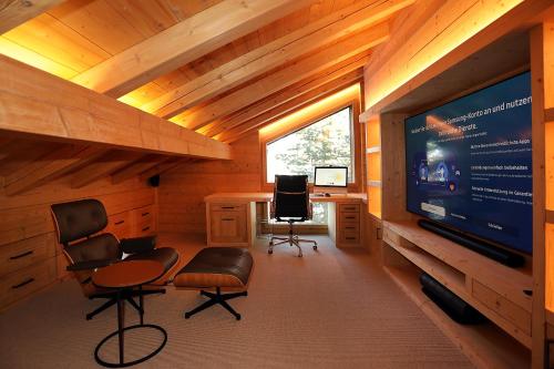 a living room with a large television and a desk at The Chalet Davos, Chesa Surlej in Davos