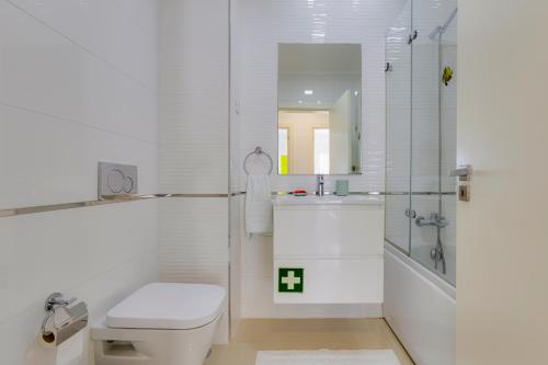 a white bathroom with a toilet and a shower at Charming 3 Bedroom Apartment Close to Historic Center-Lagos in Lagos