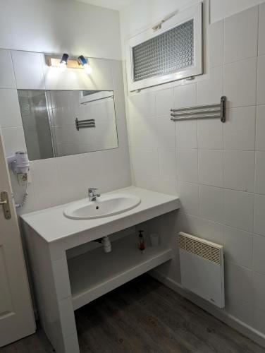 une salle de bain blanche avec un lavabo et un miroir dans l'établissement Appartement T2 bord de plage, à Sartène