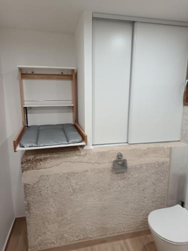 Elle comprend une petite salle de bains pourvue de toilettes et d'une étagère. dans l'établissement Le gîte vertugadin, à Sainte-Vertu