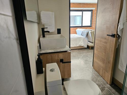 a bathroom with a toilet and a sink and a bed at Torre Luum by Duna Stays in Guadalajara