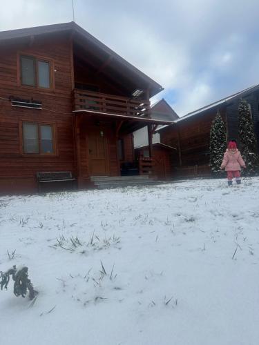 a little girl standing in the snow in front of a house at Cabana Irina Băile Figa in Beclean