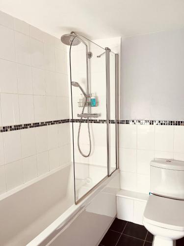 a white bathroom with a shower and a toilet at Bee Cottage in Sandown