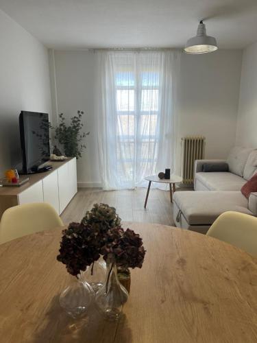 a living room with a table with a vase of flowers on it at Ruavieja, camino y vino in Logroño