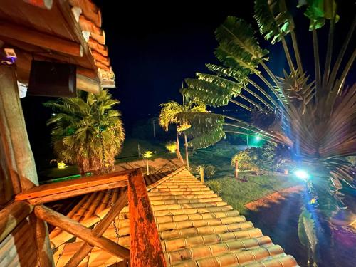 a view of a house with palm trees at night at Rancho Recanto da Serra in Delfinópolis