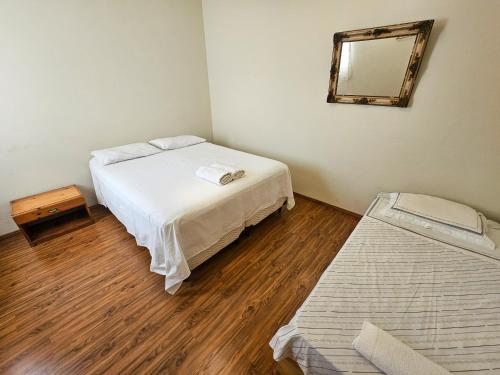 a bedroom with two beds and a mirror on the wall at Atalho Guest House in Cunha