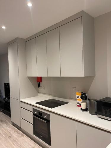a kitchen with white cabinets and a stove top oven at Cozy room in a shared apartment in Lucan