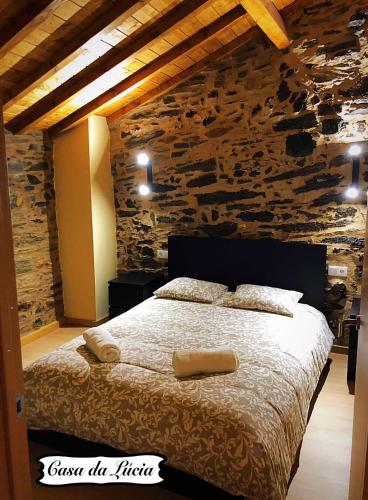 a bedroom with a large bed in a stone wall at Casa da Lúcia in Bragança