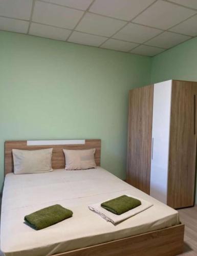 a bedroom with a bed with two green towels on it at Хотел Елит in Kostinbrod
