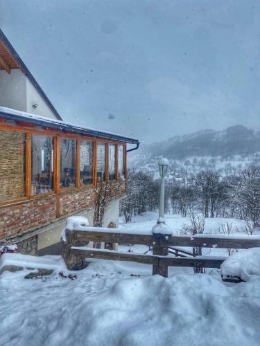 a house with a bench in the snow at Konak Umoljani in Umoljani