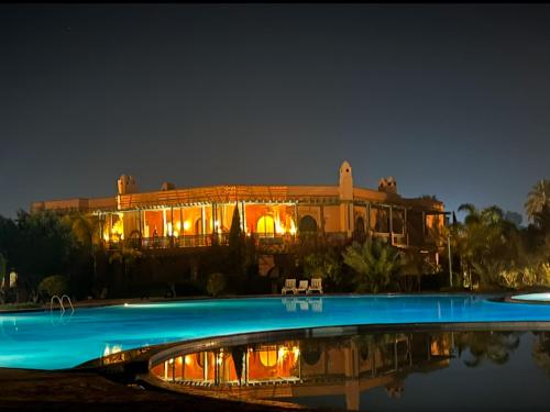 un grande edificio con piscina di notte di Palmeraie 5 Vue Piscine et Jardin a Marrakech