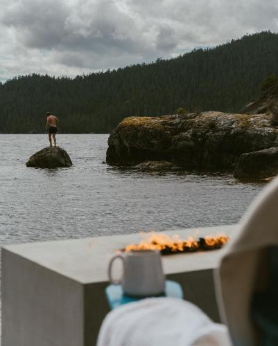a man standing on a rock in the water at Lux Remote Glamping Hideaway in Ucluelet