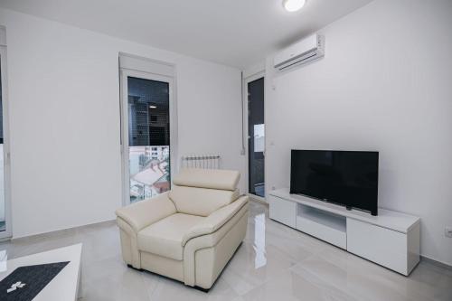 a living room with a chair and a flat screen tv at LUST PREMIUM Apartments in Kragujevac