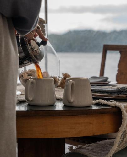 a person is pouring liquid into a cup on a table at Lux Remote Glamping Hideaway in Ucluelet