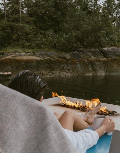 a woman laying on a boat with a pizza at Lux Remote Glamping Hideaway in Ucluelet